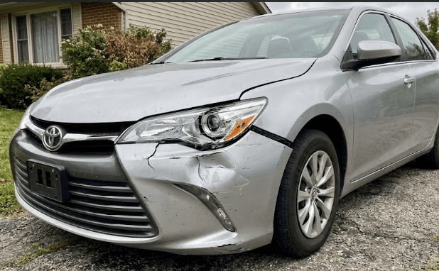 AI-generated photo of a silver sedan with front-end collision damage parked in a residential driveway.